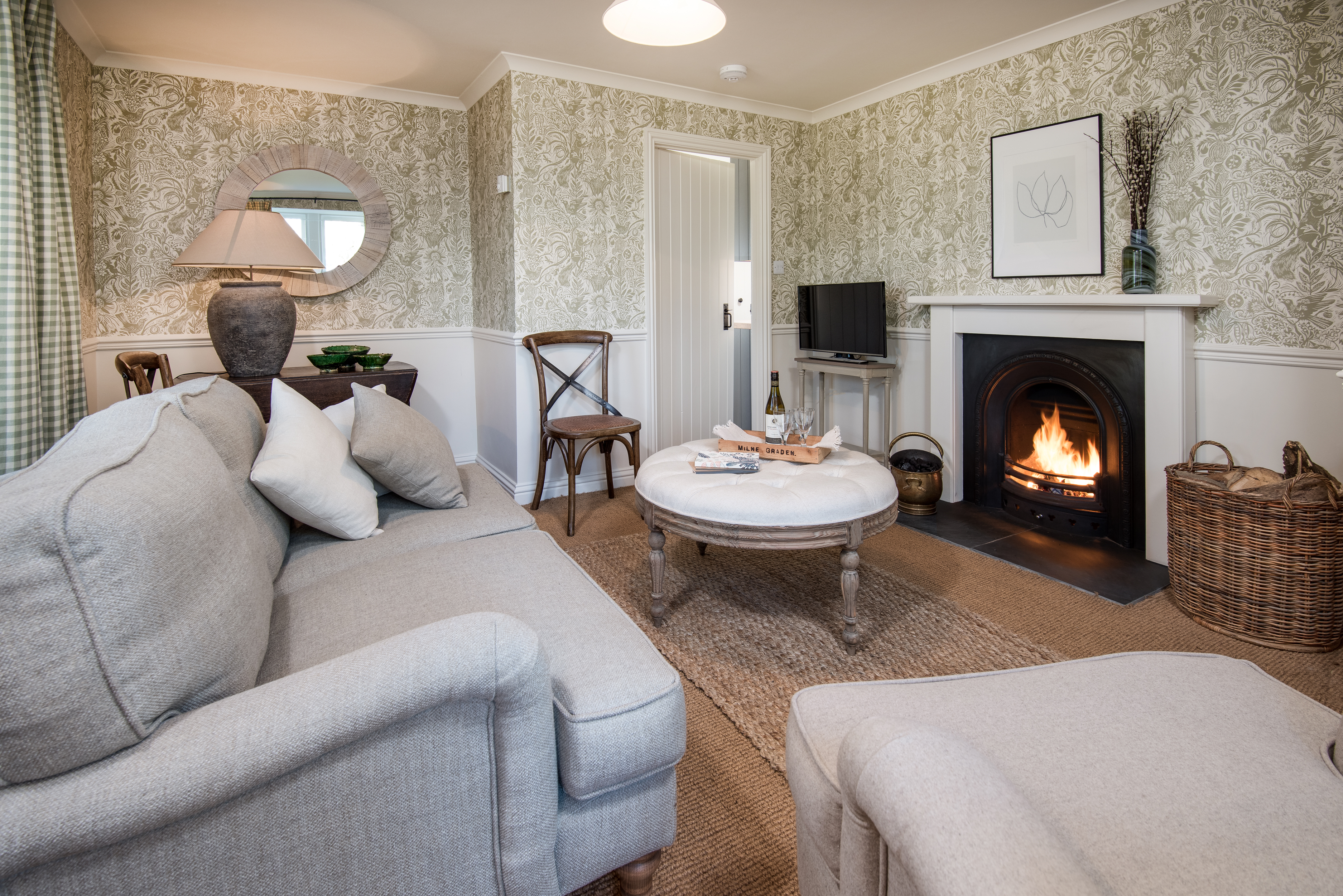 Milne Graden holiday cottage North Lodge Lounge featuring Harris Tweed Chelsea Textiles designer wallpaper open fire