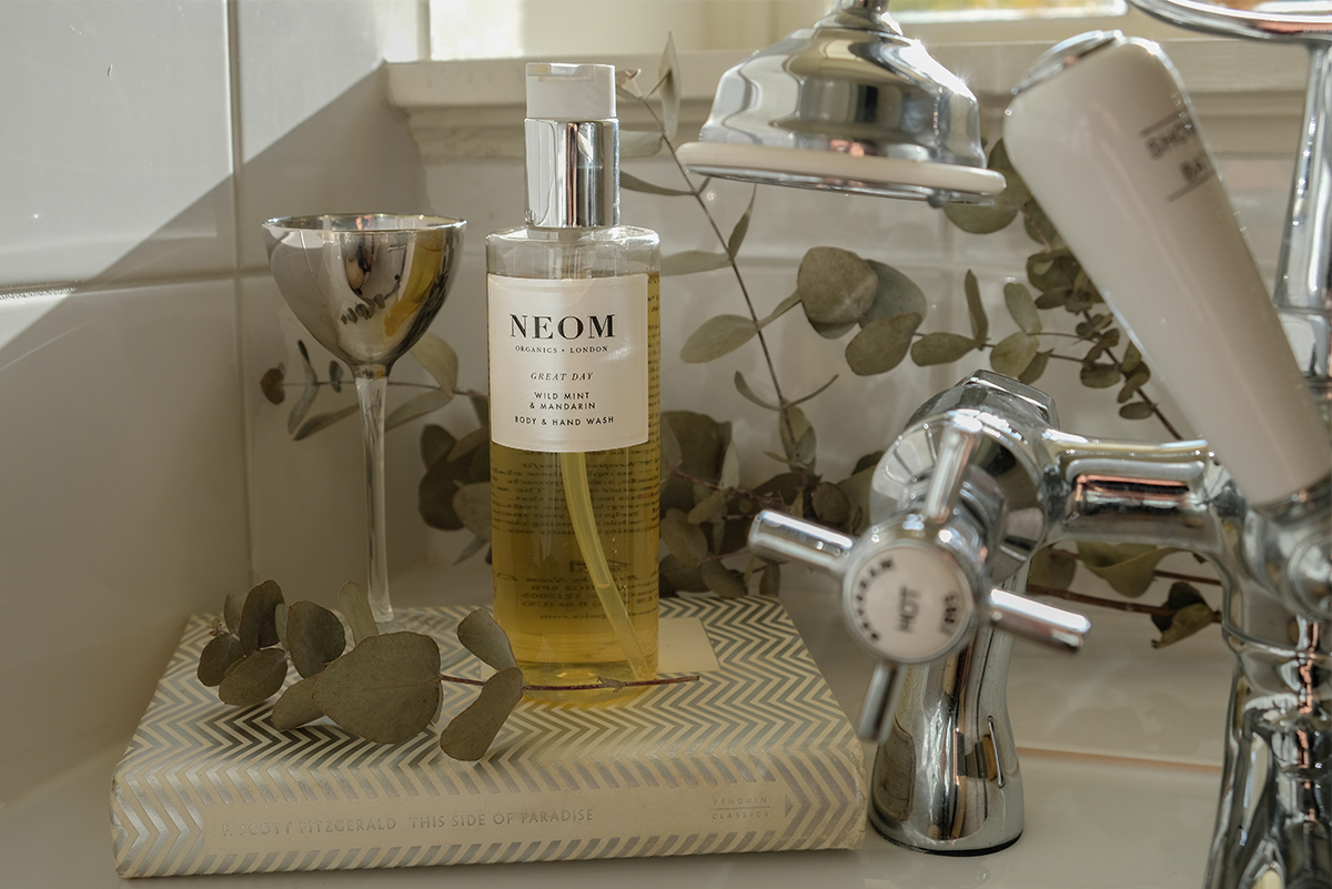 Milne-Graden-Neom-A-Scent-to-Make-You-Happy-Body_wash-on-bath-with-book-and-glass-in-Hamilton-House-Holiday-Cottage-