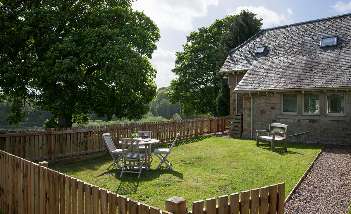 Looking-over-wooden-fence-to-outdoor-table-and-chairs-at-Tweedside-Holiday-Cottage-Dog-Freindly-Enclosed-Garden